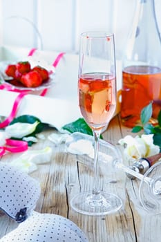 Champagne flute filled with pink champagne and strawberry pieces on a decorative table after a celebration or festivity
