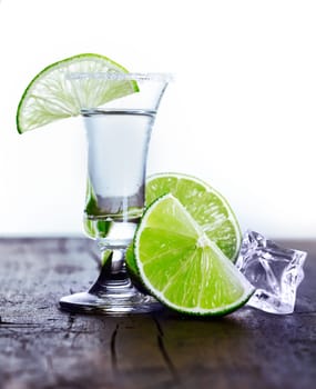 Tall glass with cool drink and lime slice with ice and lime on an outdoor table