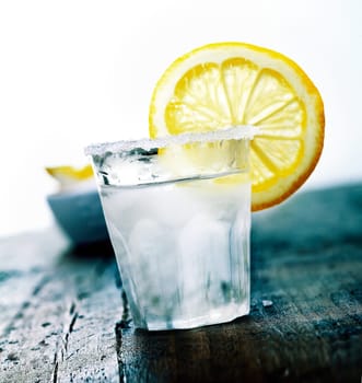 Cooled Tequila with a fresh Citron and salt on a wooden background
