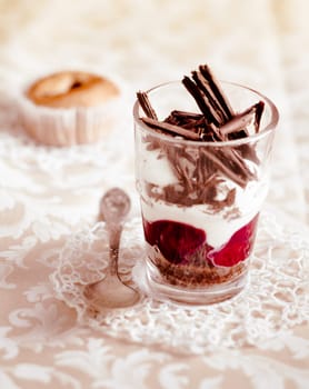 Gourmet fruit and cream parfait topped with chocolate shavings and served in a clear glass on a decorative doily