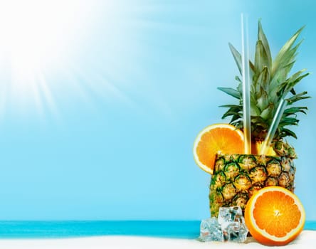 Fresh pineapple with oranges, tubules and ice on sunny beach with copy space