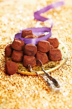 chocolate truffles with a ribbon on a festive golden background