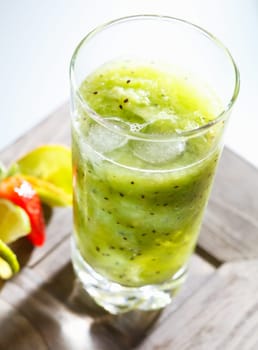 Cold and refreshing kiwi fruit smoothie served with ice in a tall glass for a healthy vegetarian breakfast