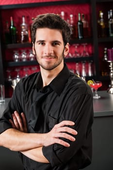 Portrait of handsome barman standing in front of the bar