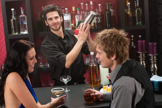 Barman making cocktail for young couple at the bar