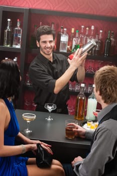 Barman making cocktail for young couple at the bar