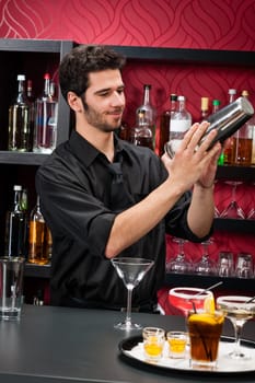 Handsome barman professional at posh bar making cocktail drinks