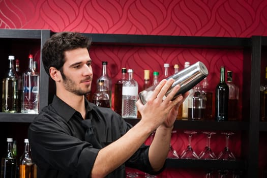 Handsome barman professional at posh bar making cocktail drinks