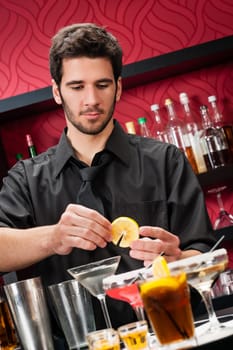 Handsome barman professional at posh bar making cocktail drinks