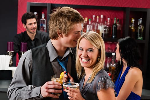 Flirting young happy friends enjoy drinks at cocktail bar