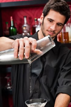 Handsome barman professional at posh bar making cocktail drinks
