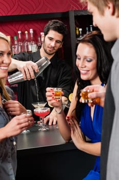 Barman making cocktail for young friends at the bar