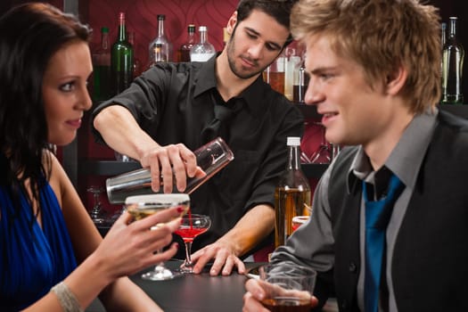 Barman making cocktail for young couple at the bar