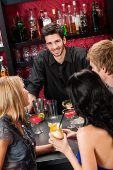 Cheerful barman chatting with young friends at cocktail bar