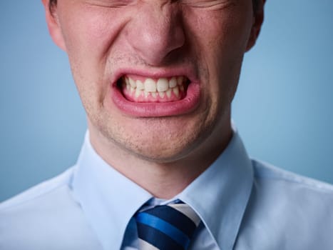 closeup of businessman screaming against blue background. Horizontal shape