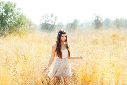 Asian indian woman walking in golden dried grass field