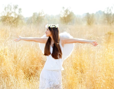 Angel etchnic woman in golden field with feather white wings and flowers crown