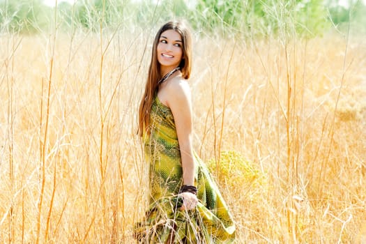Asian indian woman walking outdoors in golden field with green long dress