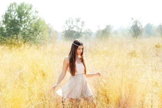 Asian indian woman walking in golden dried grass field