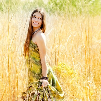 Asian indian woman walking outdoors in golden field with green long dress