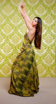 Asian Indian woman dancing full length with ethnic dress on green wallpaper