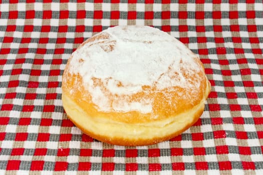 Doughnut sprinkled with sugar on dishtowel with a checkered pattern