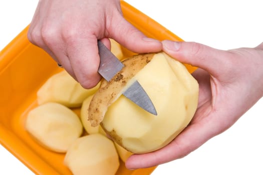 human hands peeling potatoes with a knife