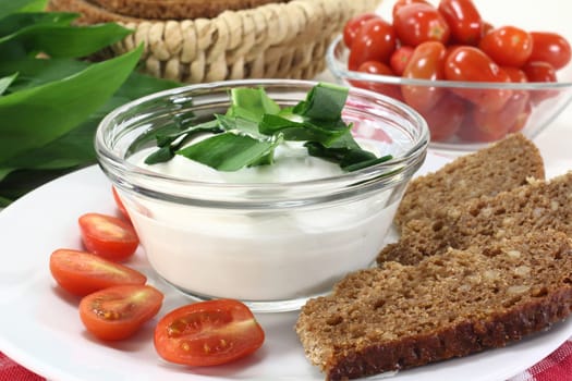 a bowl of wild garlic quark with bread and tomatoes