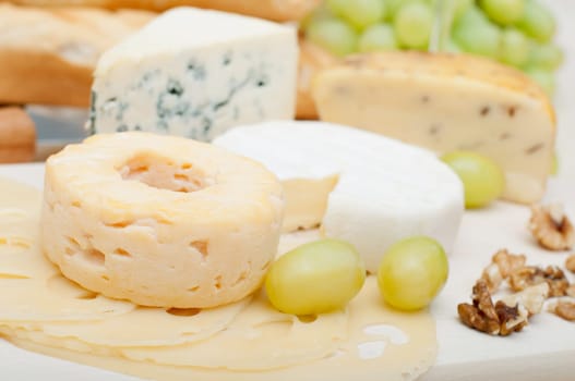 Various Types of Cheese, Grapes and Walnuts on Wooden Chopping Board