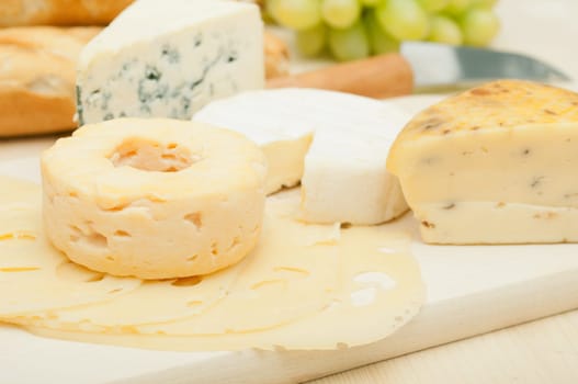 Various Types of Cheese and Grapes on Wooden Chopping Board