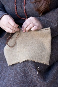 Old seamstress sewing next to the bales of hay