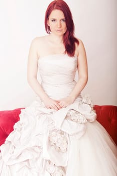 young red haired beautiful bride on red sofa
