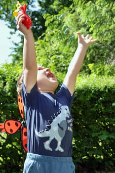 Little boy in the summer park blowing bubbles - trapping bubbles