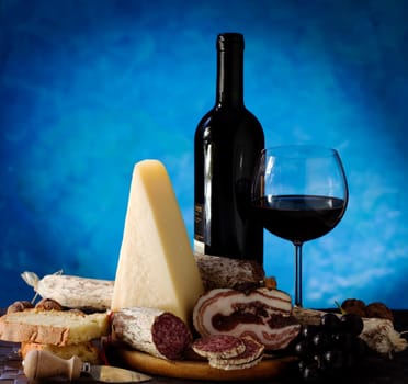 Salumi armiggiano cheese, and glass of red wine on purple background