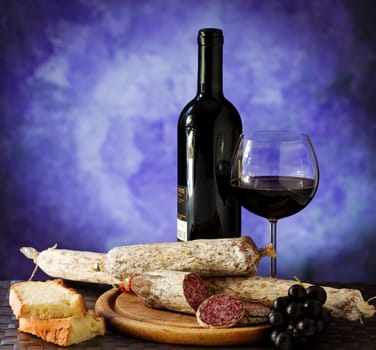 Salumi armiggiano cheese,  and glass of red wine on purple background