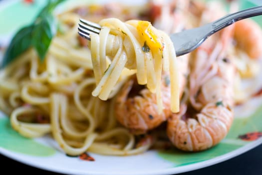 A fork of spaghetti with tomato sauce, basil and shrimp