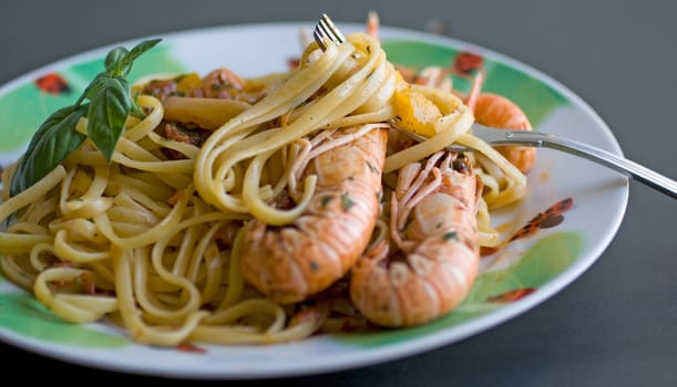A fork of spaghetti with tomato sauce, basil and shrimp