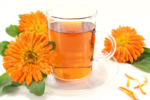 a glass of calendula tea and marigolds against a light background