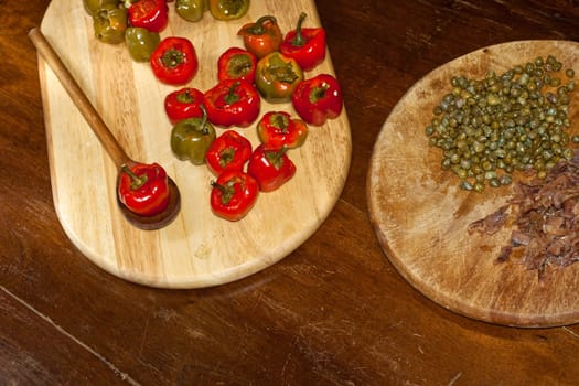 Red hot chili peppers on cutting board, capers and anchovies