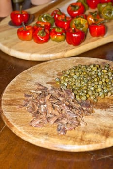 Red hot chili peppers on cutting board, capers and anchovies