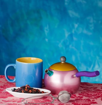 Teapot, cup and herbs on blue background