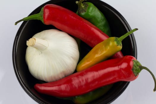 A black bowl containing garlic and chillies