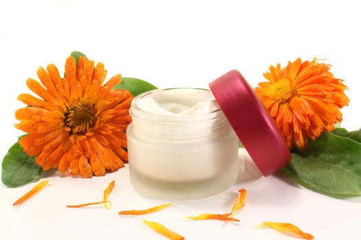 a pot of calendula ointment with fresh flowers