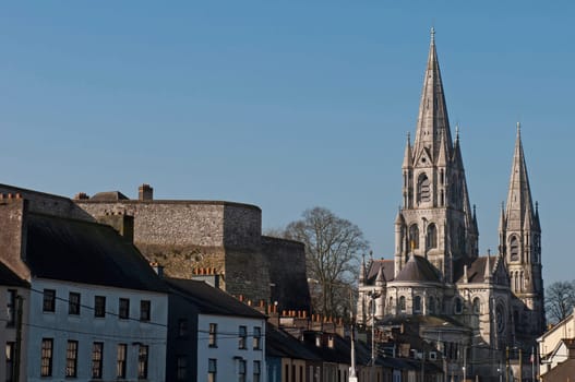 Cork cityscape featuring at the left Elizabeth Fort and on the right Saint Fin Barre&#039 s Cathedral, Ireland (blue sky background)