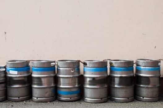 row of beer kegs against a light pink wall (copy-space available)