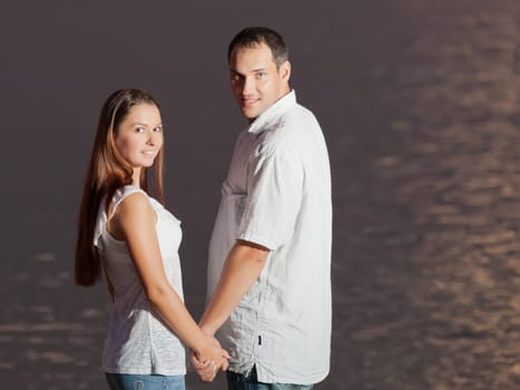 Young couple near the sea at sunrise