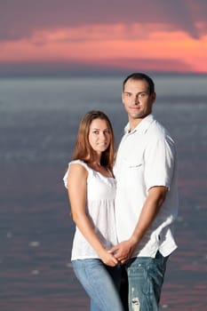 Young couple near the sea at sunrise