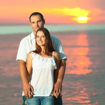 Young couple near the sea at sunrise