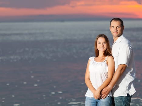 Young couple near the sea at sunrise