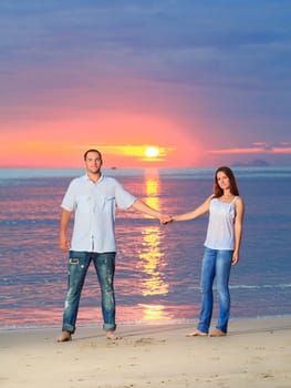 Young couple near the sea at sunrise